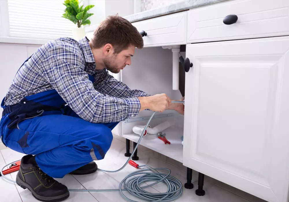 Skilled plumber performing maintenance on kitchen plumbing